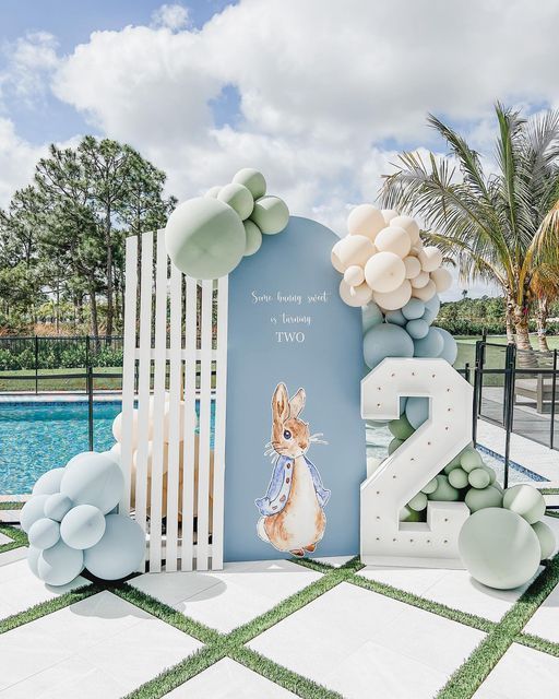 a blue and white backdrop with balloons in the shape of numbers is shown next to a pool