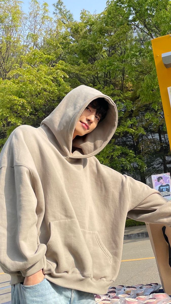 a man in a hoodie standing next to a sign with donuts on it