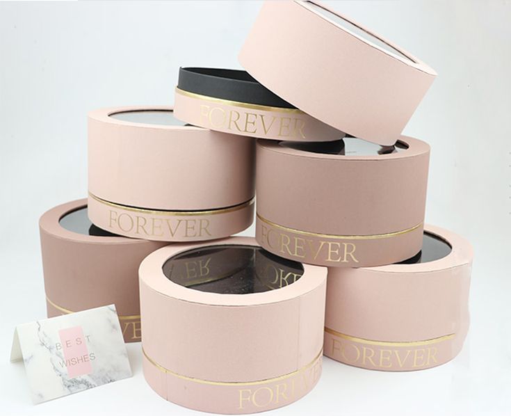 five pink boxes with gold foil lettering on them and one has a tag in the middle