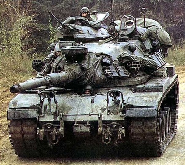 an army tank with soldiers on top driving down a dirt road