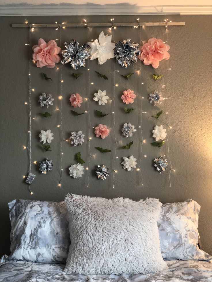 a bed with flowers and lights on the headboard, hanging over it's pillows