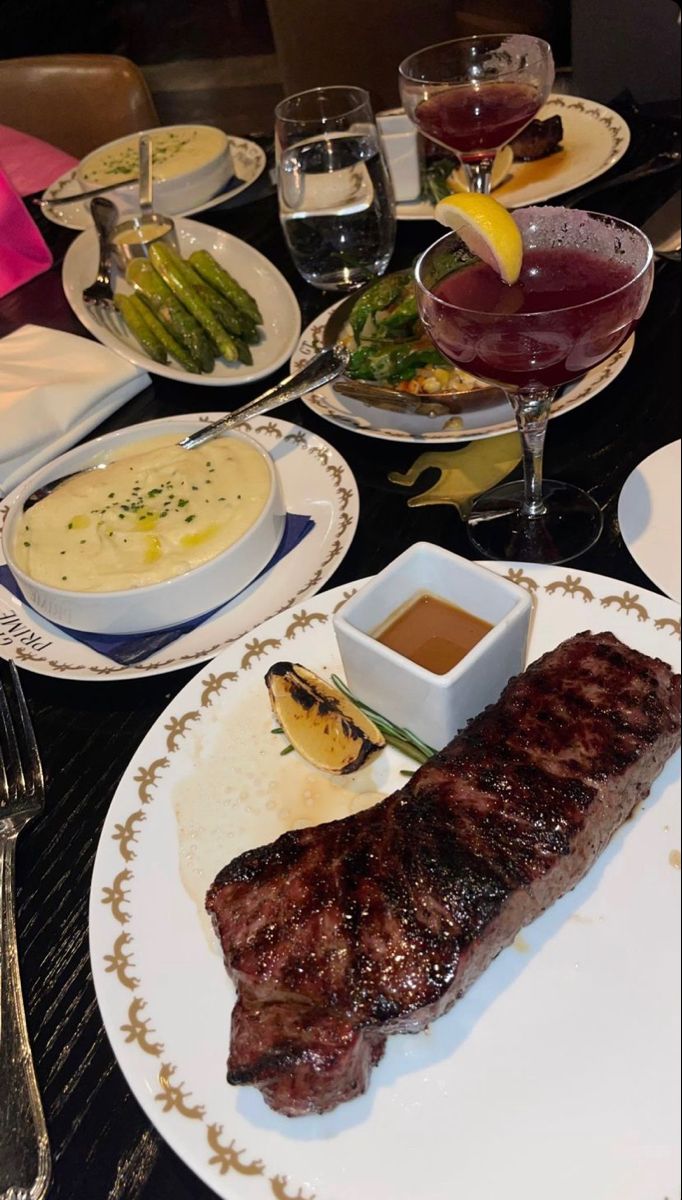 a table topped with plates and bowls filled with different types of food next to wine glasses