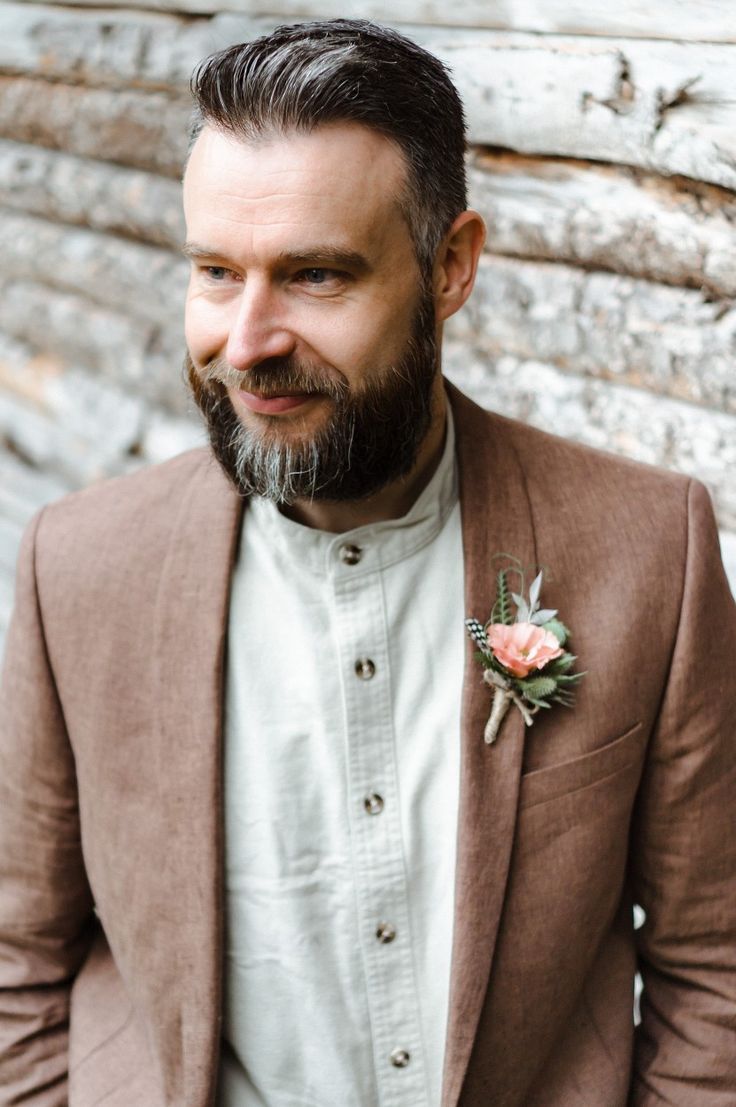 a man with a beard wearing a suit and flower boutonniere