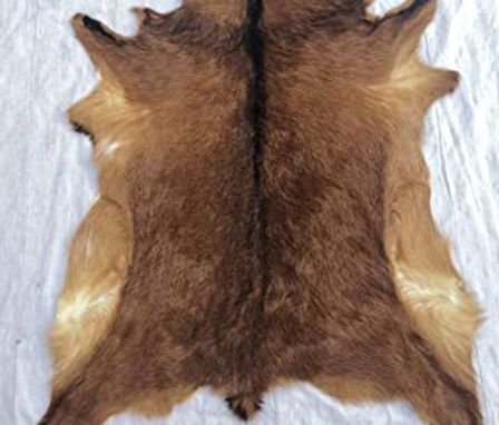 two brown and white sheepskin rugs laying on top of each other