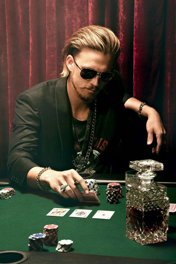 a man sitting at a table with cards and poker chips in front of his face