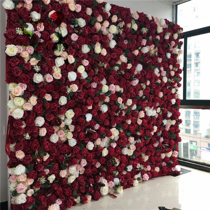 there is a large flower wall with many flowers on it in front of a window