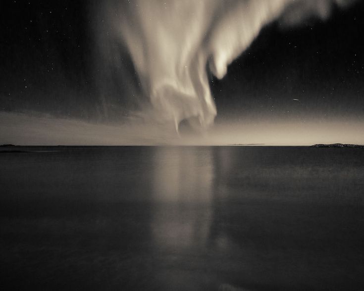 an aurora bore in the night sky over water