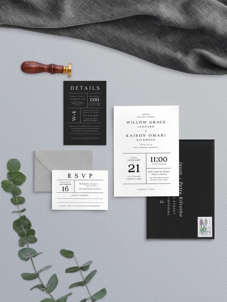 wedding stationery with black and white paper, greenery and calligraphy on it