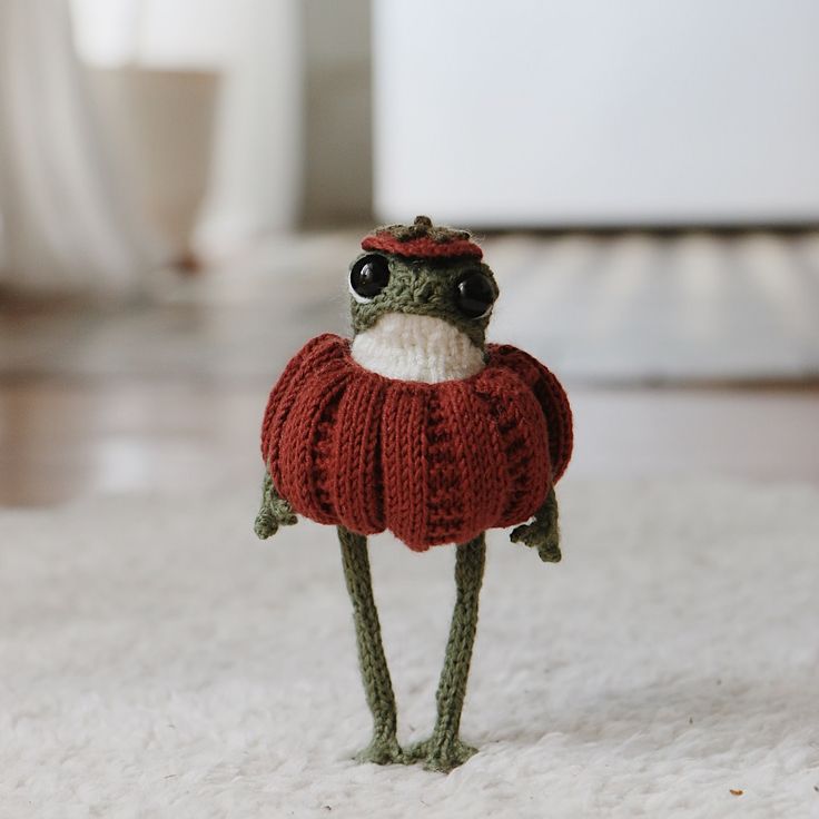 a small toy frog wearing a sweater and eyeglasses is standing on the floor