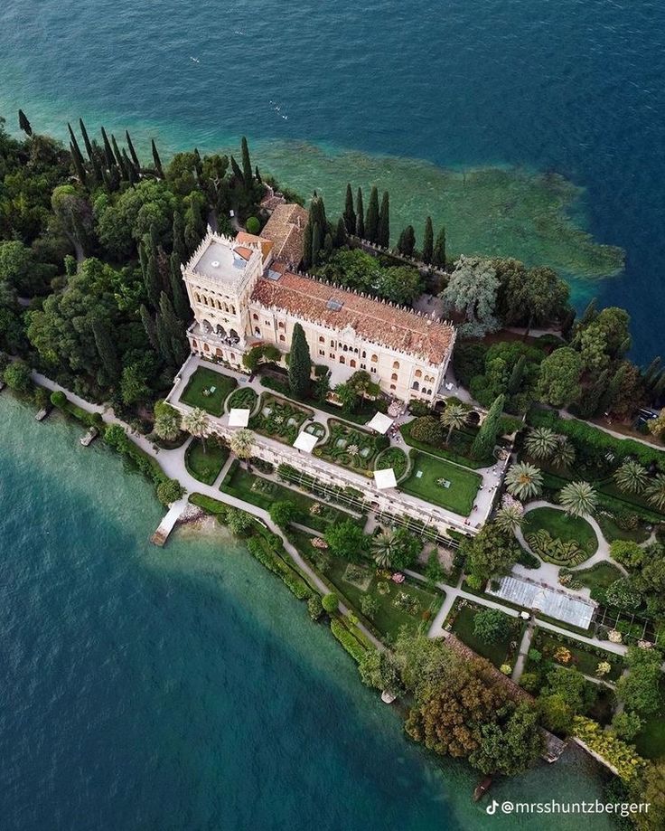 an aerial view of a large building in the middle of water with trees around it