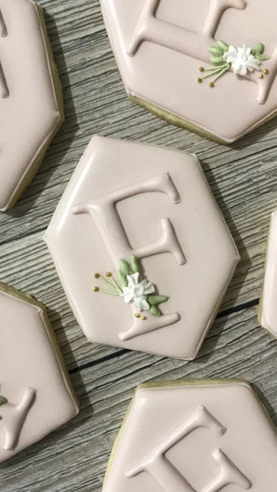 decorated cookies with the letter f on them sitting on top of a wooden table next to each other