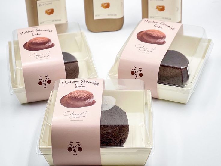 four different types of chocolates in small boxes on a white table with pink ribbon