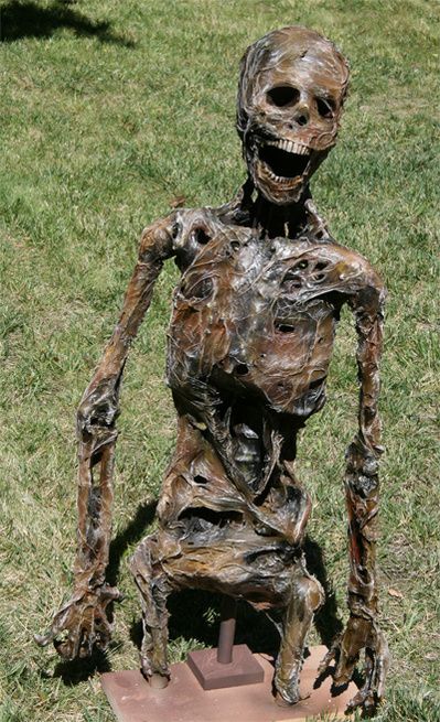 a sculpture of a human being sitting in the grass