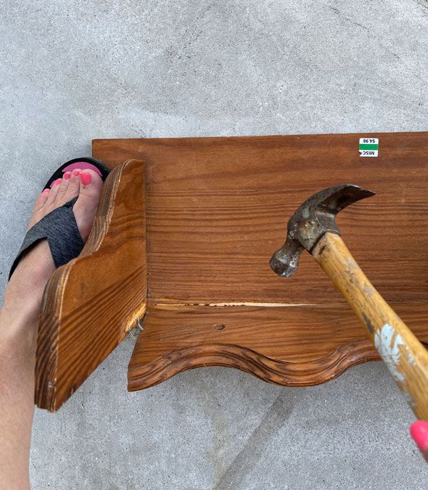 a person is holding an hammer over a wooden table with a piece of wood on it