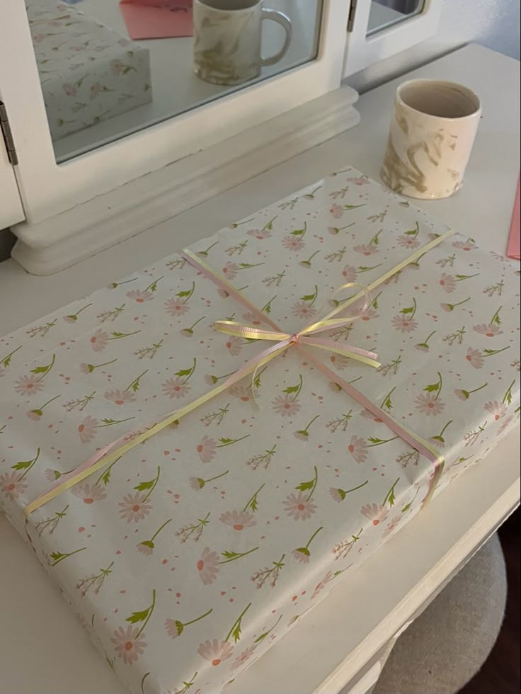 a wrapped present sitting on top of a table next to a cup and microwave oven