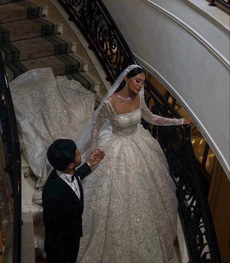 the bride and groom are walking down the stairs at their wedding ceremony in an elegant dress