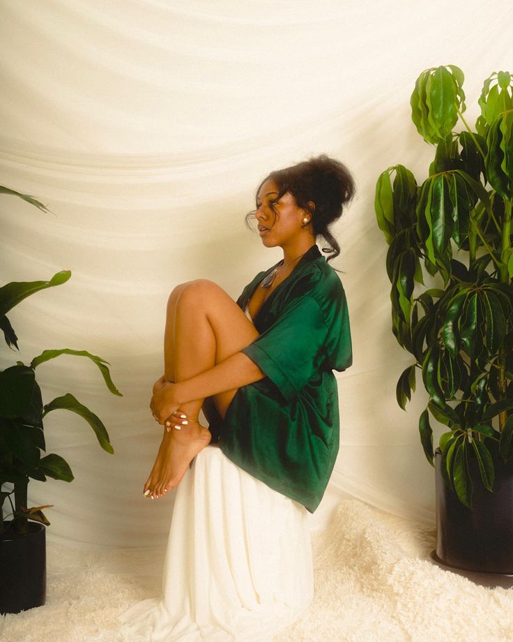 a woman sitting on top of a white chair next to a green potted plant