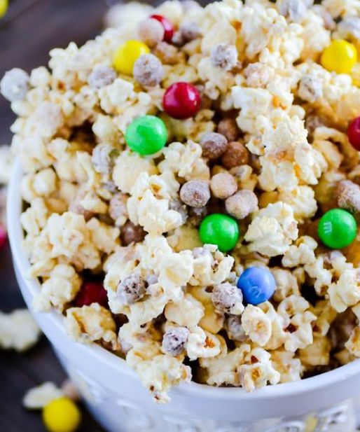 a white bowl filled with cereal and m & m candies on top of a table