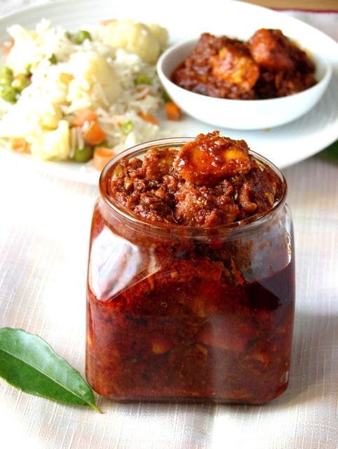 a jar filled with chili sauce sitting on top of a table next to a plate of food