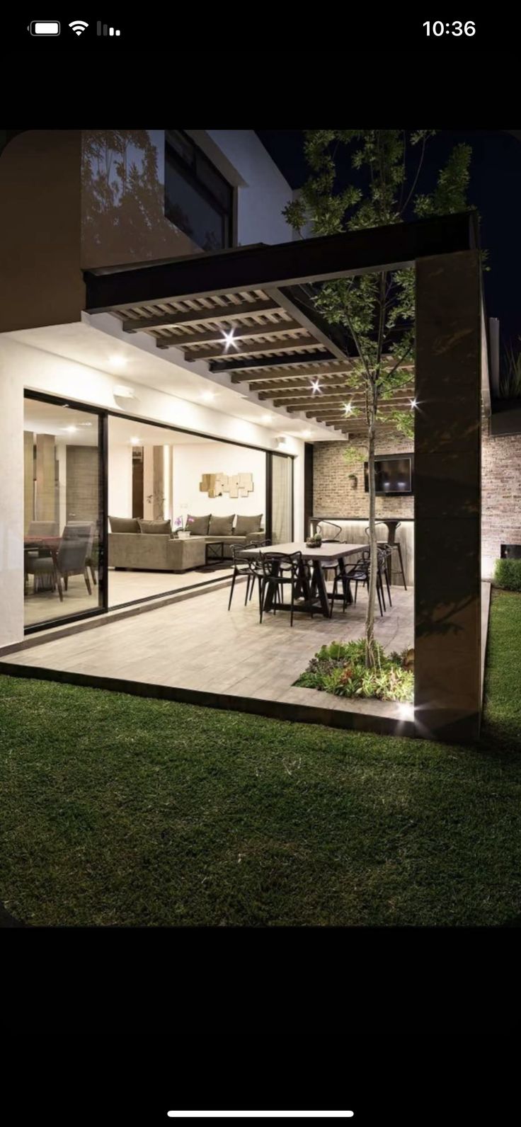 an outdoor living room and dining area are lit up at night