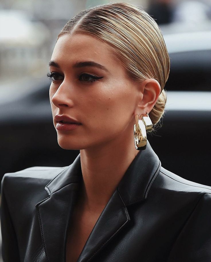 a woman in black jacket and gold earrings