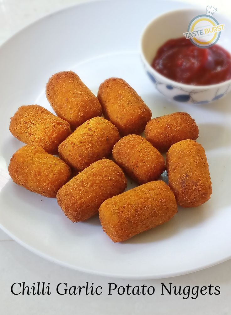 some fried food on a white plate next to a small bowl of ketchup