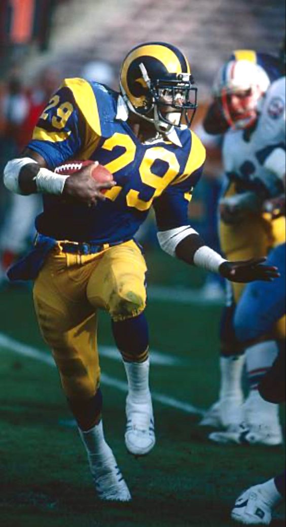 a football player running with the ball in his hand and other players on the field behind him