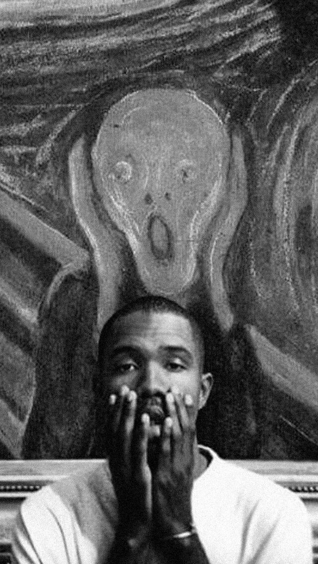 a black and white photo of a man covering his face in front of a painting