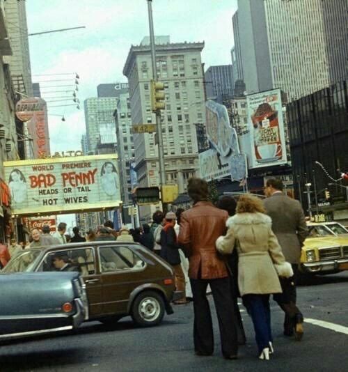 an old photo of people walking on the street in front of cars and billboards