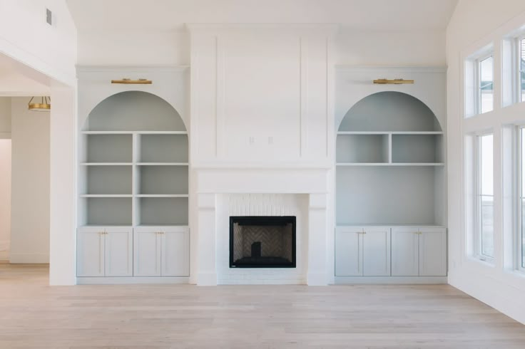 an empty living room with built - in bookshelves and fireplace