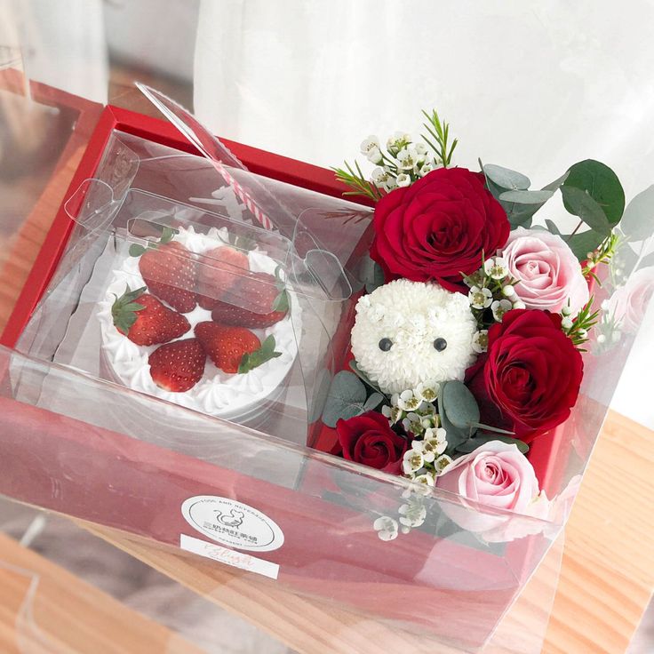 two cakes in a box with flowers and strawberries