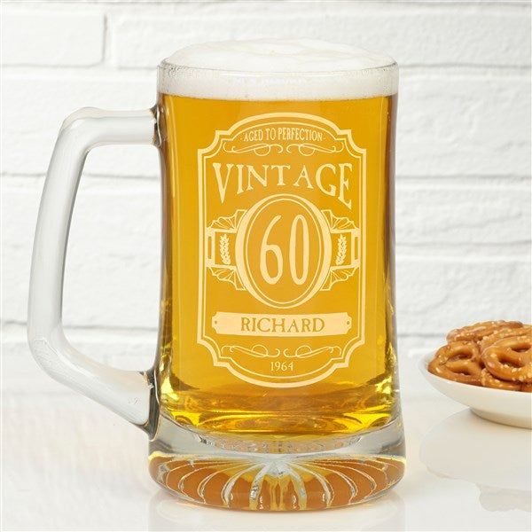 a beer mug sitting on top of a table next to a bowl of pretzels