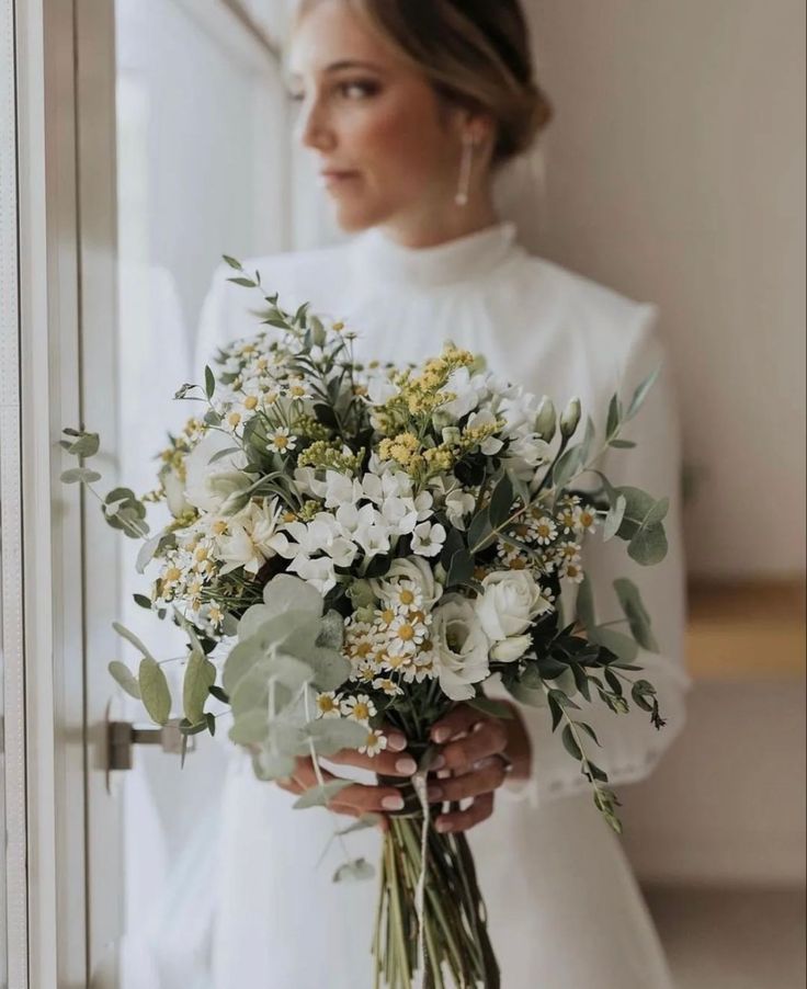 a woman holding a bouquet of flowers in her hands