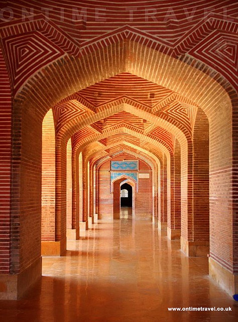 an archway in the middle of a building with red brick walls and arches on both sides