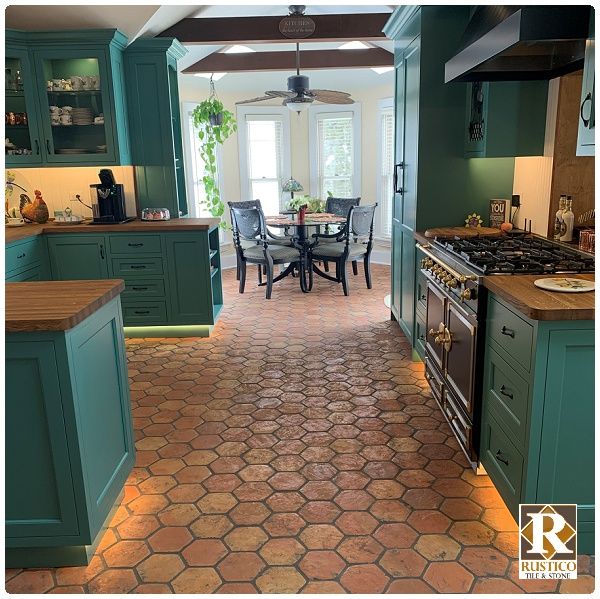 a kitchen with green cabinets and tile flooring, along with a dining room table