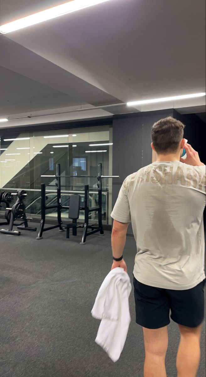 a man is walking in the gym talking on his cell phone