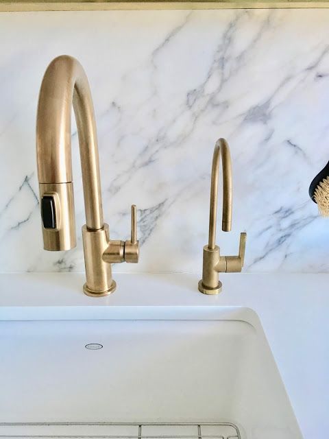 a white sink sitting under a faucet next to a marble counter top in a kitchen