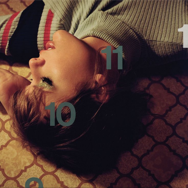 a woman laying on top of a bed next to a wall with numbers in front of her