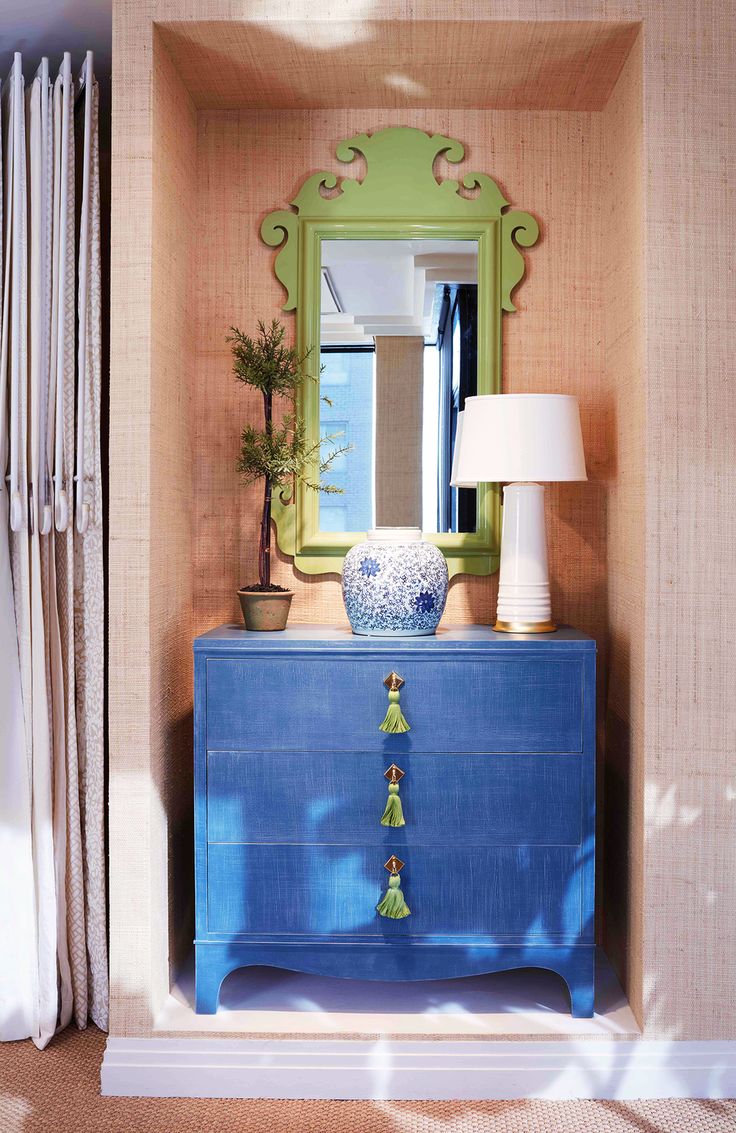 a blue dresser with a green mirror and lamp