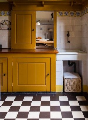 a kitchen with yellow cabinets and black and white checkered flooring on the walls