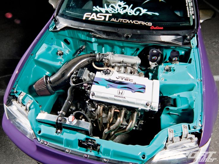 the engine compartment of a purple car with blue paint and chrome trim, parked in a parking lot