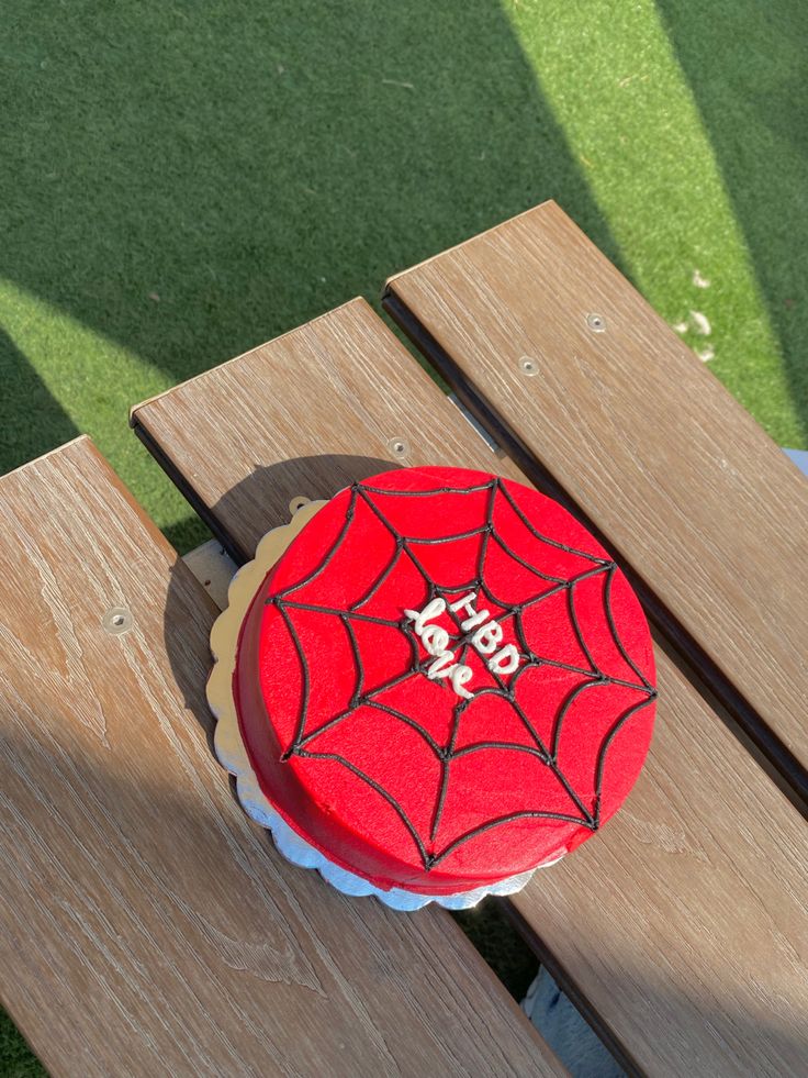 a spiderman cake sitting on top of a wooden bench