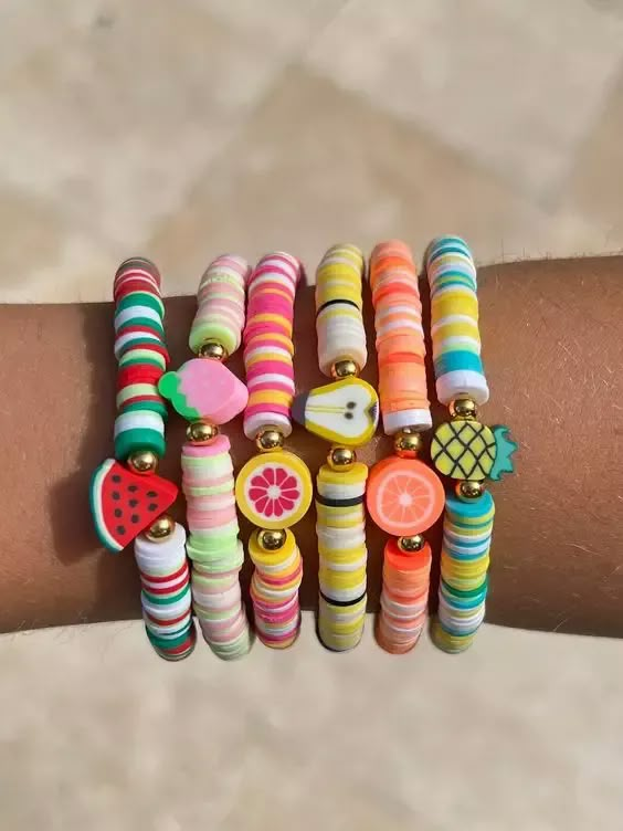 a person's arm with several bracelets on it and fruit charms attached to them