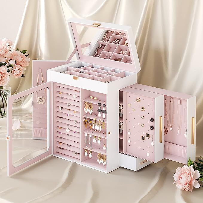 an open pink jewelry box sitting on top of a table next to flowers and vase