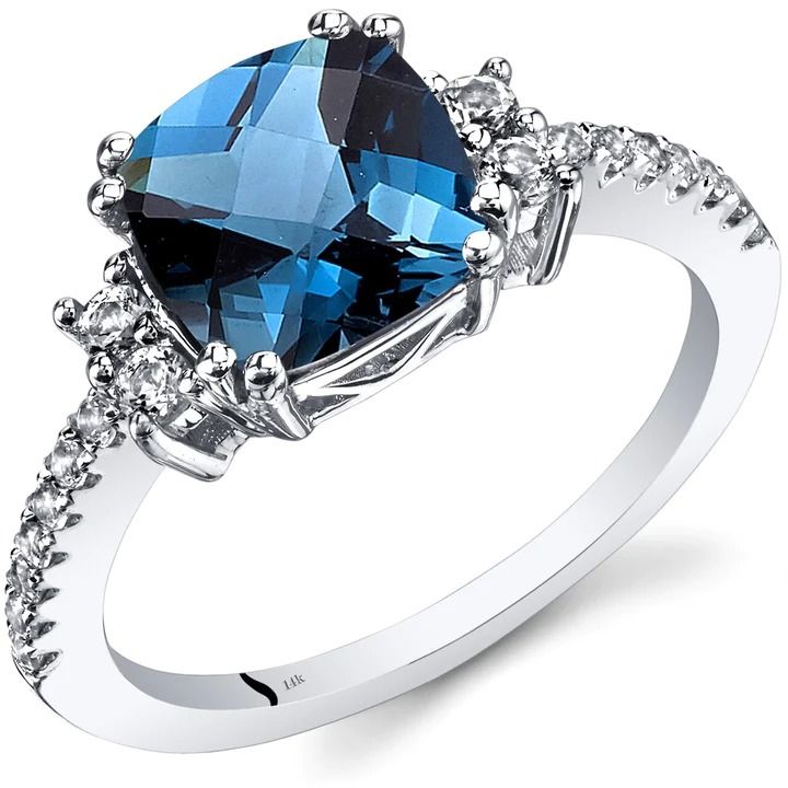 a large blue stone surrounded by diamonds on a white gold ring with an accent band