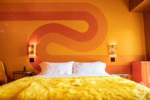 a bedroom with orange walls and yellow fur on the bed, along with two nightstands