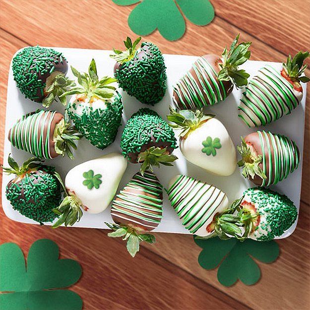 green and white strawberries are arranged on a platter with shamrocks for st patrick's day