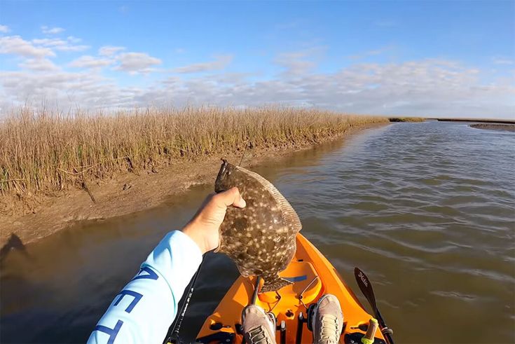 a person in a kayak is holding an object up to the water's edge