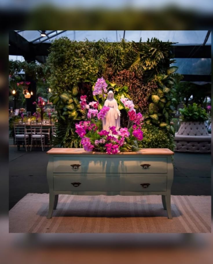 a table with flowers and a statue in the middle on display at a flower show