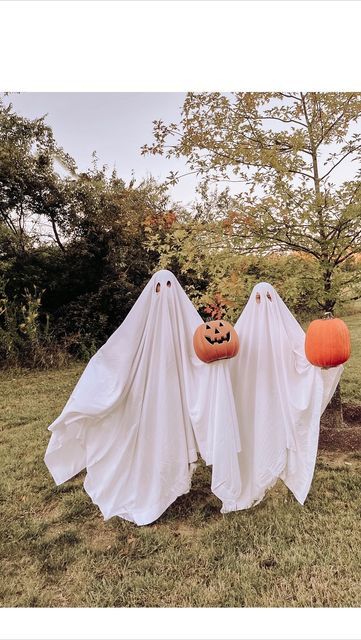 two pumpkins in the shape of ghostes hanging from trees